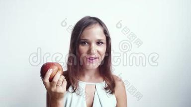 美丽的年轻女子吃着红苹果水果微笑着看着镜头。 孤立在白色背景上。 4k，3840x2160